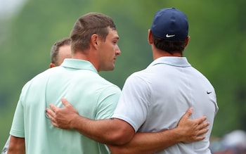 Bryson DeChambeau of the United States and Brooks Koepka of the United States embrace on the 18th green