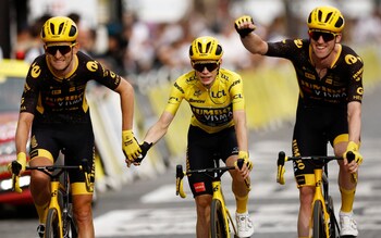 Jonas Vingegaard crosses the line hand-in-hand with team-mate Tiesj Benoot to seal his overall victory in the Tour de France