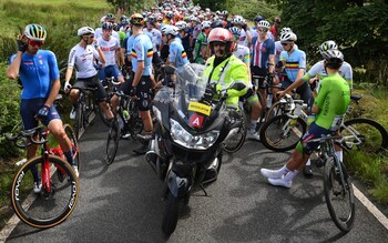 Riders wait for the men's road race at the Cycling World Championships to resume following a protest – Transgender protester brings Cycling World Championships road race to a halt