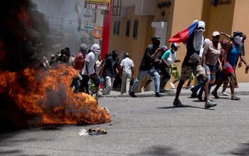 Protesters walk past a burning barricade during a demonstration to demand security against gangs in Port-au-Prince