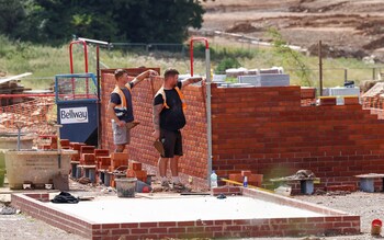 Construction workers lay bricks on a housing development 